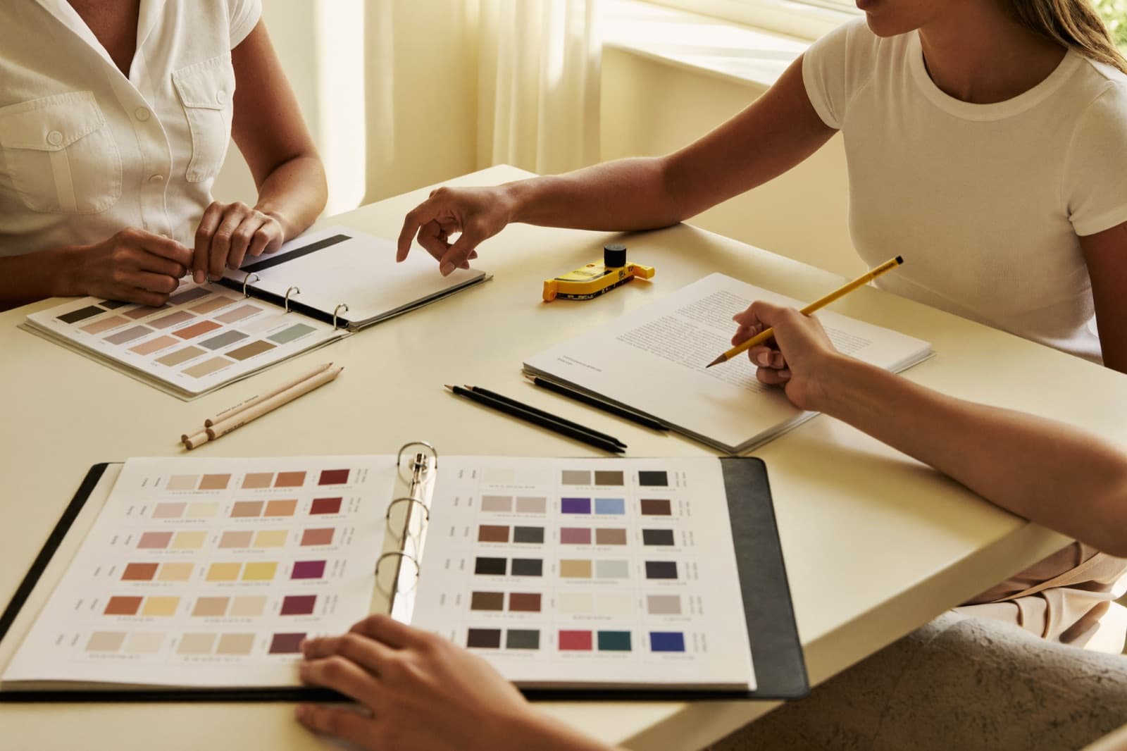 Farblehre am Tisch: Pigment-Farbfächer, Stifte und Messwerkzeug während einer Unterrichtssituation